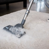 Cleaner using vacuum cleaner with hot steam on carpet at home